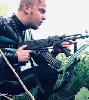 convicted cyberstalker and olean ny resident luke wenke crouching among foliage in a latex gimp suit with an ar-style firearm